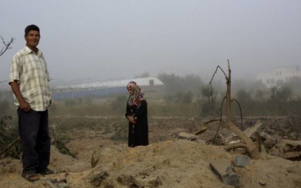 Un homme et une femme palestinienne inspectent les lieux après un raid de l'armée israélienne à Khan Younes (Crédit : AFP/MOHAMMED ABED)