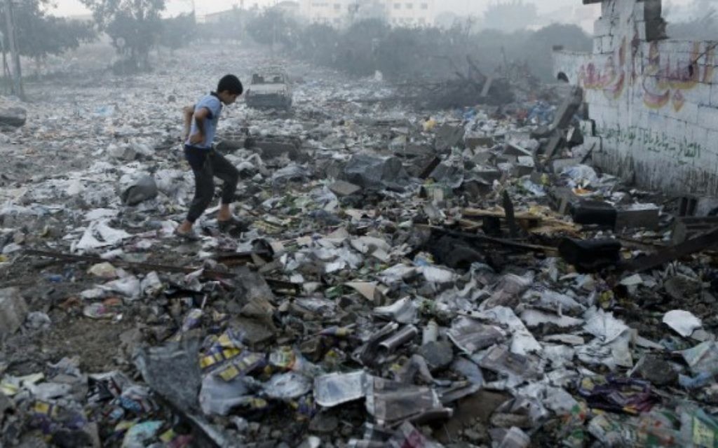 Un jeune Palestinien marche sur les débris suite à un raid aérien israélien dans la ville de Gaza, le 24 Juillet, 2014 (Crédit : MOHAMMED ABED)