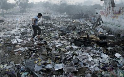 Un jeune Palestinien marche sur les débris suite à un raid aérien israélien dans la ville de Gaza, le 24 Juillet, 2014 (Crédit : MOHAMMED ABED)