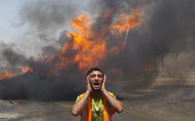 Un pompier palestinien tente d'éteindre le feu provoqué par une frappe aérienne israélienne (Crédit : AFP/Mahmud Hams)