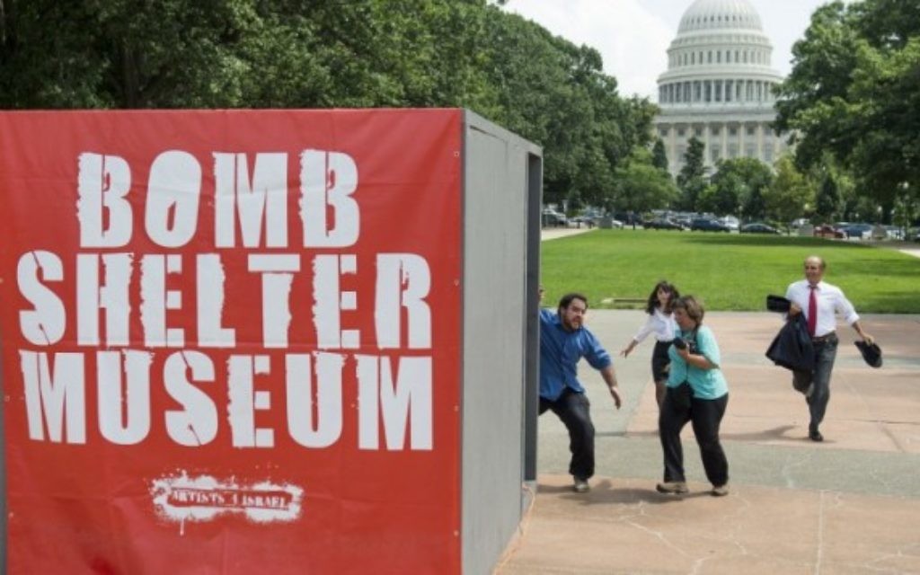 Les gens courent vers une maquette d'un abri anti-bombes lors d'une attaque simulée par les roquettes du Hamas dans le cadre d'une exposition d'art multimédia appelée "Le Musée Bomb Shelter" qui s'inspire des abris en Israël, près du Capitole des États-Unis à Washington, le 22 Juillet 2014. (Crédit : AFP / Saul Loeb)