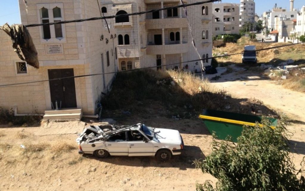 Une voiture détruite à cause des pierres de la maison qui sont tombées à l'extérieur (Crédit : Elhanan Miller/Times of Israel)