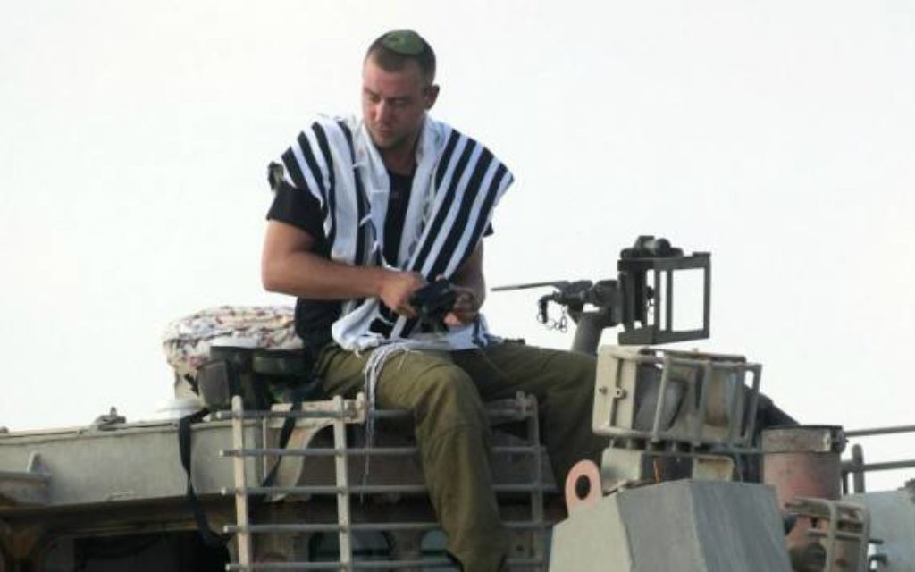 Un soldat israélien priant sur un char de l'armée (Crédit : David Buimovitch/Flash90)