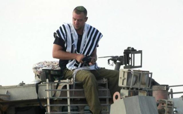 Un soldat israélien priant sur un char de l'armée (Crédit : David Buimovitch/Flash90)