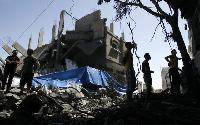 Palestiniens marchant parmi les décombres d'une maison détruite suite à un tir de missile israélien, à Rafah le 14 juillet, 2014 (Crédit : Abed Rahim Khatib/Flash90)