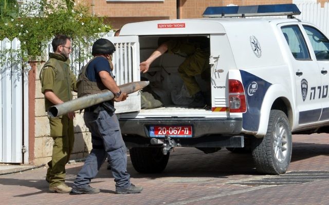 Des hommes de la sécurité israéliens transportent un débris d'une roquette à Ashkelon (Crédit : Flash 90) Des hommes de la sécurité israéliens transportent un débris d'une roquette à Ashkelon (Crédit : Flash 90)