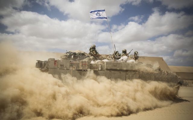Un APC passe à travers les serres abandonnées près de la frontière israélienne avec Gaza le 25 juillet 2014, alors que les forces israéliennes se rassemblent pour entrer à Gaza. (Crédit : Hadas Parush/FLASH90)