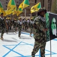 Membres irakiens du Hezbollah tiennent les drapeaux jaunes de la branche irakienne du parti chiite et un portrait de guide spirituel de l'Iran, l'ayatollah Ruhollah Khomeini, et ils marchent sur ​​un drapeau israélien peint sur ​​le sol pendant la journée d'al-Qods (Jérusalem) - 25 Juillet 2014, la capitale irakienne Bagdad. (Crédit : AFP / Ali al-Saadi)