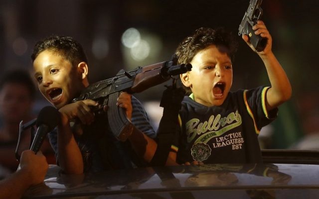 Des enfants lèvent des armes en l'air (dont une avec un chargeur vide) sur une voiture alors que les Palestiniens se rassemblent dans les rues pour célébrer après un accord conclu entre le Hamas et Israël - 28 août 2014 (Crédit : AFP PHOTO / MOHAMMED ABED) Des enfants lèvent des armes en l'air (dont une avec un chargeur vide) sur une voiture alors que les Palestiniens se rassemblent dans les rues pour célébrer après un accord conclu entre le Hamas et Israël - 28 août 2014 (Crédit : AFP PHOTO / MOHAMMED ABED)