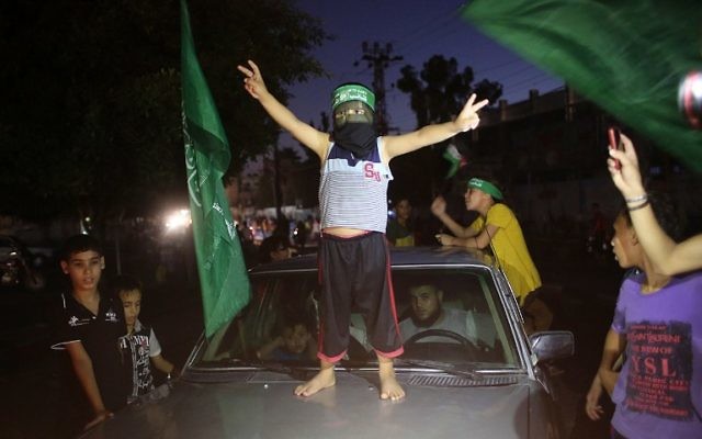 Un enfant palestinien avec un bandeau du Hamas fait le signe de la victoire sur une voiture alors que les gens se rassemblent dans les rues pour célébrer l'accord de trêve conclu entre le Hamas et Israël, à Rafah, dans le sud de la bande de Gaza, le 26 août 2014. (Crédit : AFP PHOTO / SAID KHATIB) Un enfant palestinien avec un bandeau du Hamas fait le signe de la victoire sur une voiture alors que les gens se rassemblent dans les rues pour célébrer l'accord de trêve conclu entre le Hamas et Israël, à Rafah, dans le sud de la bande de Gaza, le 26 août 2014. (Crédit : AFP PHOTO / SAID KHATIB)