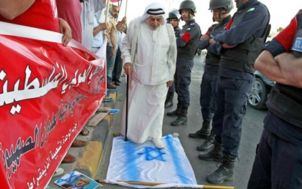 Un manifestant jordanien marche sur un drapeau national israélien. Il prend part à une manifestation devant l'ambassade américaine à Amman, le 3 Août 2014 contre le soutien américain à l'offensive israélienne dans la bande de Gaza. (Crédit : AFP/KHALIL MAZRAAWI)