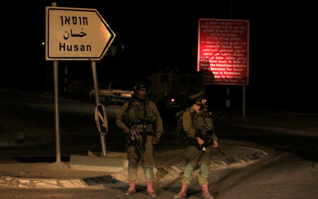 Des soldats israéliens devant l'entrée du village Hussan (Crédit : Oren Nahshon / Flash90)