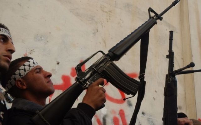 Un Palestinien masqué des Brigades des martyrs d'al-Aqsa, une branche armée du mouvement Fatah du président de l'AP Mahmoud Abbas, détient une arme tout en parlant aux médias à Balata  - camp de réfugiés près de Naplouse, février 2008 (Crédit : Wagdi ASHTIYEH / Flash90 )