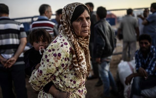 Une réfugiée kurde syrienne tient un bébé après avoir franchi la frontière près de la ville sud-est de la province de Sanliurfa Suruc, le 21 septembre, 2014 (Crédit : AFP PHOTO / BULENT KILIC) Une réfugiée kurde syrienne tient un bébé après avoir franchi la frontière près de la ville sud-est de la province de Sanliurfa Suruc, le 21 septembre, 2014 (Crédit : AFP PHOTO / BULENT KILIC)
