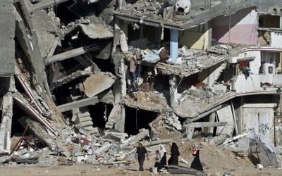 Une famille passe devant les ruines d'immeubles à Shejaiya, dans la bande de Gaza, le 27 août 2014. (Crédit : AFP/Roberto Schmidt)