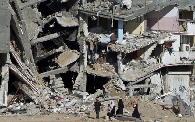 Une famille passe devant les ruines d'immeubles à Shejaiya, dans la bande de Gaza, le 27 août 2014. (Crédit : AFP/Roberto Schmidt) Une famille passe devant les ruines d'immeubles à Shejaiya, dans la bande de Gaza, le 27 août 2014. (Crédit : AFP/Roberto Schmidt)
