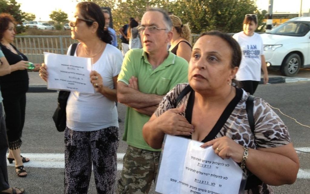 Ilanit Cheikh, une résidente d'Ariel porte une pancarte  où l'on peut lire "ne pas laisser les Arabes monter dans le bus, c'est du racisme, ne pas laisser les Israéliens monter dans le bus n'est pas du racisme," 4 septembre, 2014 (Crédit : Elhanan Miller / Times of Israel)