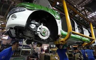 Des travailleurs iraniens construisant une Peugot 206 le 11 octobre 2014 à Téhéran (Crédit : AFP/ATTA KENARE)