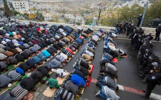 Des jeunes palestiniens prient devant un cordon de policiers israéliens dans le quartier de Wadi al-Joz à Jérusalem-Est 31 octobre 2014. (Crédit : Yonatan Sindel / Flash90)