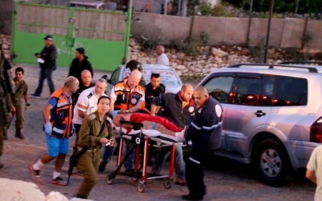Le personnel de sécurité et de secours israéliens vus avec le terroriste qui a été abattu après une attaque au couteau mortelle à un arrêt de bus à l'entrée de Alon Shvut, le 10 novembre, 2014. (Crédit : Gershon Elinson / Flash90)