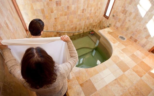 Une femme entrant dans le mikvé, le bain rituel juif  (Crédit : JTA / Mayyim Hayyim)