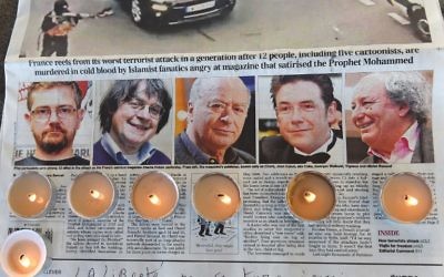 Des bougies placées sur un journal montrant les photos du rédacteur en chef et dessinateur de  l'hebdomadaire français satirique Charlie Hebdo Charb,, de Jean Cabut, alias Cabu, de Georges Wolinski et de Michel Renaud, tués la veille lors d'un attentat par deux hommes armés dans les bureaux du journal satirique français Charlie Hebdo, lors d'un rassemblement à Marseille, le 8 janvier 2015. (Crédit : Anne-Christine Poujoulat/AFP)