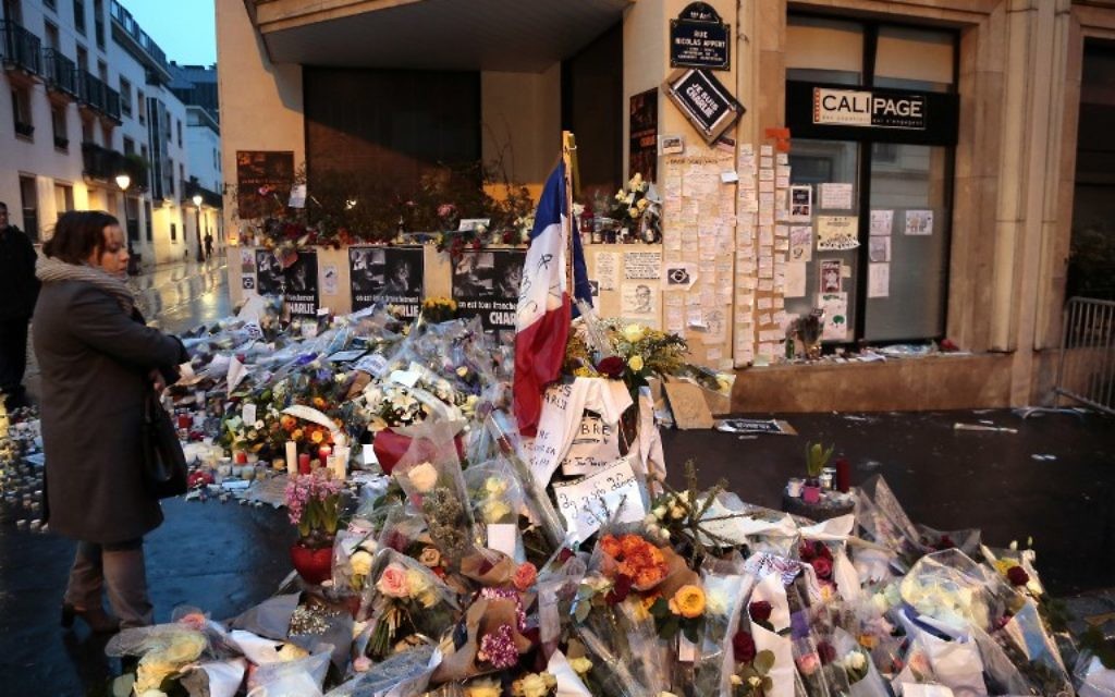 Une femme contemple les fleurs déposées devant les bureaux du magazine Charlie Hebdo à Paris pour les victimes du massacre du 7 Janvier (Crédit : AFP PHOTO /JACQUES DEMARTHON)