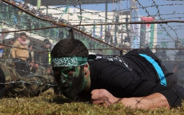 Un jeune Palestinien rampe sous un obstacle de barbelés lors d'une cérémonie de remise de diplôme pour un camp d'entraînement dirigé par le Hamas le 29 janvier 2015, à Khan Younis, dans le sud de la bande de Gaza. (Crédit : AFP / SAID KHATIB) Un jeune Palestinien rampe sous un obstacle de barbelés lors d'une cérémonie de remise de diplôme pour un camp d'entraînement dirigé par le Hamas le 29 janvier 2015, à Khan Younis, dans le sud de la bande de Gaza. (Crédit : AFP / SAID KHATIB)