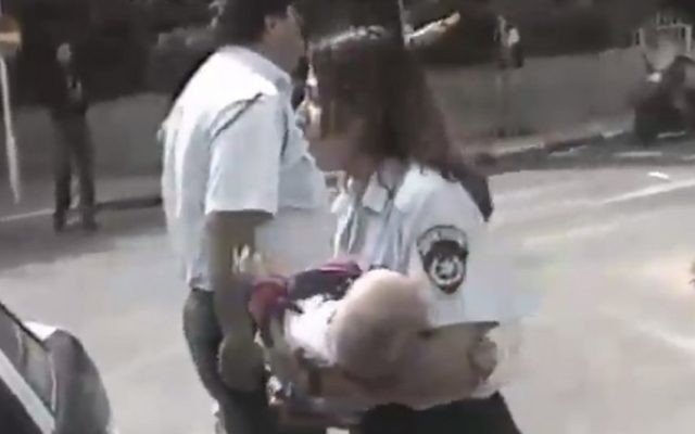 La policière Tsiona Busheri portant Shani Winter, un bébé de 6 mois, et le sauvant de l'attentat du café Apropos à Tel Aviv en mars 1997 (Capture d'écran : Deuxième chaîne) La policière Tsiona Busheri portant Shani Winter, un bébé de 6 mois, et le sauvant de l'attentat du café Apropos à Tel Aviv en mars 1997 (Capture d'écran : Deuxième chaîne)