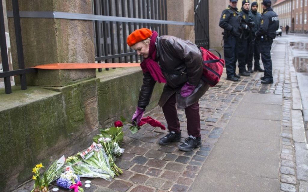 Une femme qui dépose un bouquet de fleurs devant la synagogue de Copenhague - 15 février 2015 (Crédit : AFP)