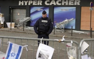 Un policier montant la garde le 21 janvier 2015 devant le magasin HyperCacher à Paris où quatre Juifs ont été  assassinés par Amédy Coulibaly, le 9 janvier 2015. (Crédit : Eric Feferberg/AFP)