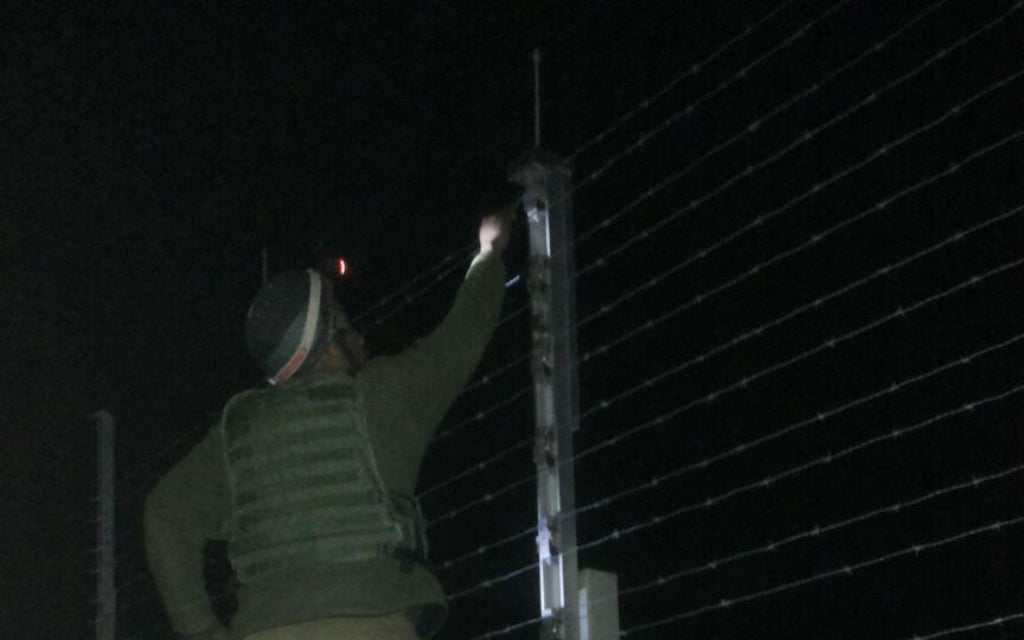 Un soldat de Kometz , debout sur une échelle du côté gazaoui de la barrière de sécurité, pour réparer la clôture. Illustration. (Crédit : Netta Asner/unité des porte-paroles de l'armée israélienne)