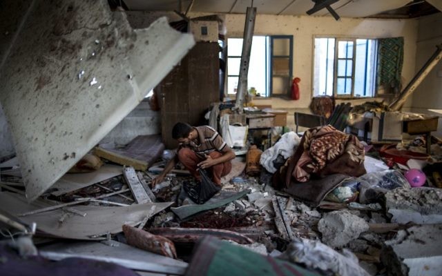 Des Palestiniens cherchent les restes des dépouilles humaines dans une salle de classe d'une école de l'ONU, à Gaza, le 30 Juillet 2014. (Crédit : AFP/Marco Longari)