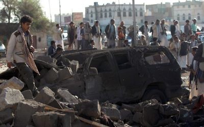 Des Yéménites se tiennent sur le site d'un raid aérien mené par l'Arabie Saoudite contre les rebelles Houthis près de l'aéroport de Sanaa le 26 mars 2015, qui a tué au moins 13 personnes. (Crédit : AFP / MOHAMMED HUWAIS)