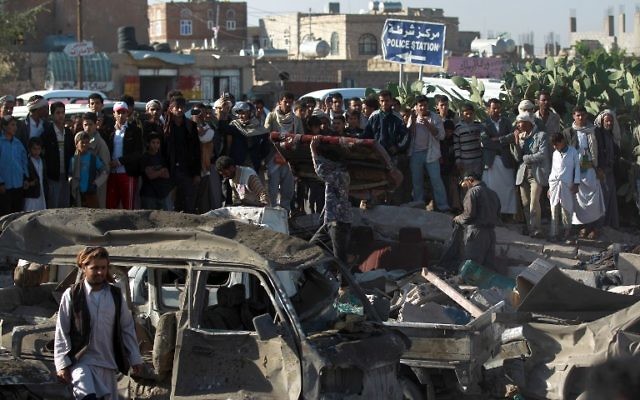 La population yéménite et les forces de sécurité se tiennent sur le site d'une frappe aérienne menée contre les Houthis près de l'aéroport de Sanaa le 26 mars, 2015, qui a tué au moins 13 personnes (Crédit : AFP PHOTO / MOHAMMED HUWAIS)