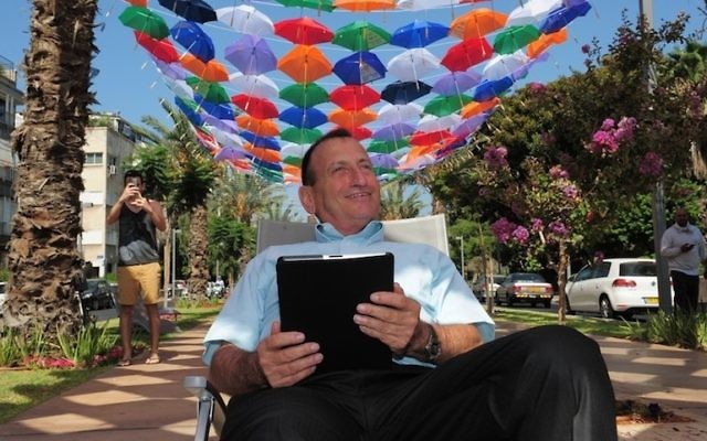 Le maire de Tel-Aviv, Ron Huldai, surfe sur Internet sous le toit de 600 parasols colorés qui décorent le boulevard Rothschild pour lancer le nouveau « cloud Wi-Fi » dans sa ville (Crédit : Kfir Sivan) Le maire de Tel-Aviv, Ron Huldai, surfe sur Internet sous le toit de 600 parasols colorés qui décorent le boulevard Rothschild pour lancer le nouveau « cloud Wi-Fi » dans sa ville (Crédit : Kfir Sivan)