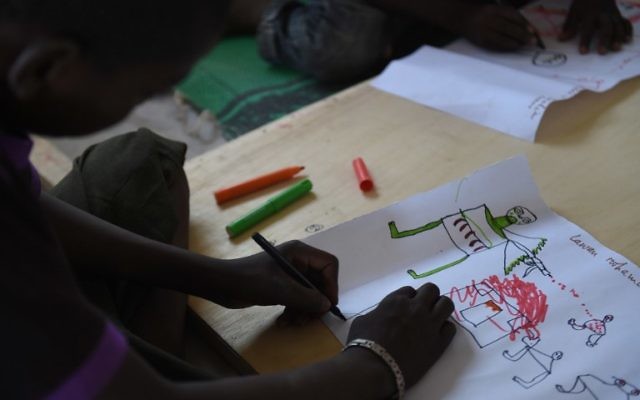 Un jeune réfugié nigérian dessine une scène d'attaque le 6 avril 2015 au cours d'une thérapie gérée par l'UNICEF dans le camp de réfugiés près de Baga Sola (Crédit : AFP PHOTO / PHILIPPE DESMAZES) Un jeune réfugié nigérian dessine une scène d'attaque le 6 avril 2015 au cours d'une thérapie gérée par l'UNICEF dans le camp de réfugiés près de Baga Sola (Crédit : AFP PHOTO / PHILIPPE DESMAZES)