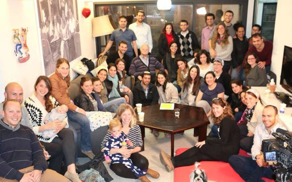 Les jeunes gens se réunissent pour écouter le témoignage du survivant de l'Holocauste Tzvi Ben Porat (deuxième à gauche, deuxième ligne à l'arrière) lors de l'événement 'Zikaron Basalon ' à la maison de la famille Malhi à Jérusalem, le 15 avril 2015 (Crédit : Noam Feiner)