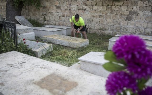 Illustration : Un jeune nettoie le cimetière arménien sur le mont Sion, près du quartier arménien de la Vieille Ville de Jérusalem, le 15 avril 2015 avant les prières qui auront lieu au cimetière en l'honneur des victimes du génocide arménien (Crédit : Hadas Parush / Flash90)