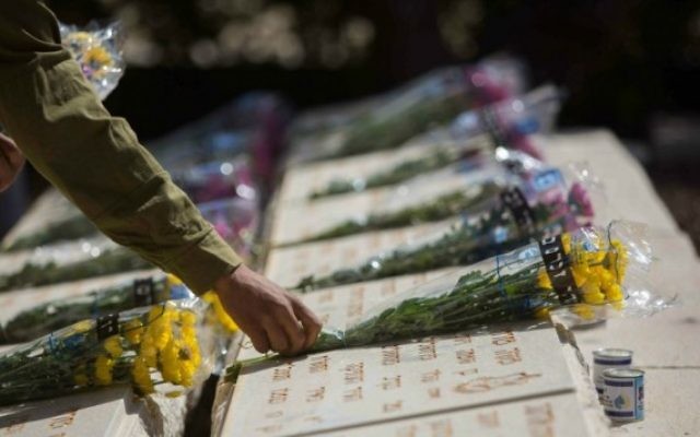 Un soldat de Tsahal dépose des fleurs sur la tombe d'un soldat tombé au combat au cours d'une cérémonie tenue au Mont des Oliviers, à Jérusalem, avant Yom Hazikaron, le 21 avril 2015. (Crédit photo: Yonatan Sindel / Flash90)