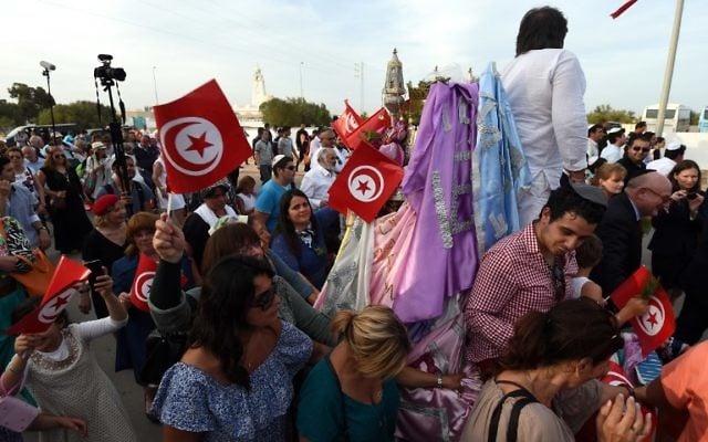 Les pèlerins juifs participent à la procession de la "Menara", une pyramide hexagonale représentant les cinq livres du prophète Moïse, en dehors de la synagogue de la Ghriba sur l'île touristique de Djerba, le 6 mai 2015. Le pèlerinage juif à la Ghriba synagogue a lieu sous une sécurité supplémentaire après le massacre du musée du Bardo et la mise en garde d'Israël de menaces terroristes existantes. (Crédit : AFP PHOTO / FETHI BELAID)