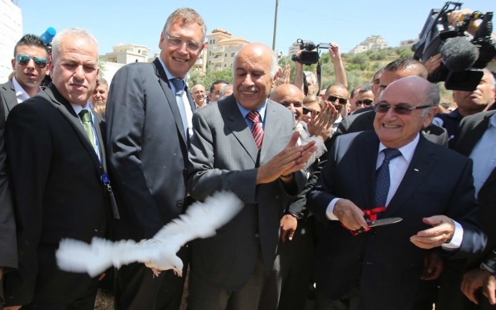 La président de la FIFA, Joseph Blatter (à droite) libère une colombe tandis que le président de l'Association de football palestinien, Jibril Rajoub (au centre) applaudit lors de sa visite au village de Dura al-Qaraa, près de la ville cisjordanienne de Ramallah, le 20 mai 2015. (Crédit : AFP / ABBAS MOMANI) La président de la FIFA, Joseph Blatter (à droite) libère une colombe tandis que le président de l'Association de football palestinien, Jibril Rajoub (au centre) applaudit lors de sa visite au village de Dura al-Qaraa, près de la ville cisjordanienne de Ramallah, le 20 mai 2015. (Crédit : AFP / ABBAS MOMANI)