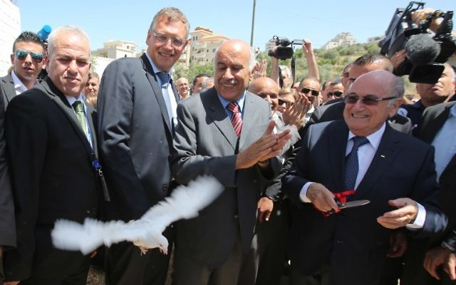 La président de la FIFA, Joseph Blatter (à droite) libère une colombe tandis que le président de l'Association de football palestinien, Jibril Rajoub (au centre) applaudit lors de sa visite au village de Dura al-Qaraa, près de la ville cisjordanienne de Ramallah, le 20 mai 2015. (Crédit : AFP / ABBAS MOMANI) La président de la FIFA, Joseph Blatter (à droite) libère une colombe tandis que le président de l'Association de football palestinien, Jibril Rajoub (au centre) applaudit lors de sa visite au village de Dura al-Qaraa, près de la ville cisjordanienne de Ramallah, le 20 mai 2015. (Crédit : AFP / ABBAS MOMANI)