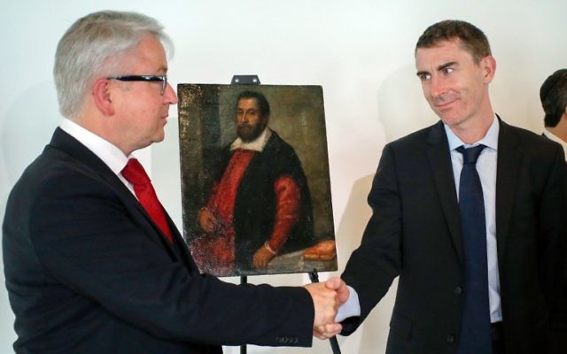 Yann Yochum, (d) Consul adjoint, responsable de la presse et de la politique, au Consulat général de France à New York, serre la main de Markus H. Stoetzel, procureur représentant héritier du Dr August Liebmann Mayer après avoir annoncé le retour de la peinture "Portrait d'un homme" perdu en raison de la persécution nazie à son héritier légitime, le 5 mai 2015 au Musée du patrimoine juif à New York. (Crédit : AFP PHOTO / Eduardo Munoz Alvarez) Yann Yochum, (d) Consul adjoint, responsable de la presse et de la politique, au Consulat général de France à New York, serre la main de Markus H. Stoetzel, procureur représentant héritier du Dr August Liebmann Mayer après avoir annoncé le retour de la peinture "Portrait d'un homme" perdu en raison de la persécution nazie à son héritier légitime, le 5 mai 2015 au Musée du patrimoine juif à New York. (Crédit : AFP PHOTO / Eduardo Munoz Alvarez)