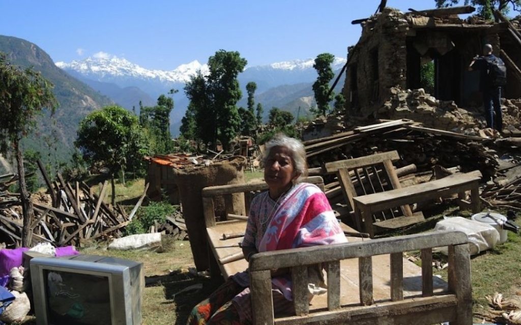 Une femme est assise avec les choses récupéréss de son domicile dans le village de Topani au Népal. Les villages avaient de l'électricité provenant d'un barrage hydroélectrique dans la rivière, mais il faudra probablement mois avant que l'électricité ne soit restauré dans cette région, mai 2015 (Crédit : Melanie Lidman / Times of Israël)