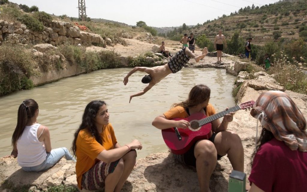Des Palestiniens et des Israéliens se rafraîchissent dans une source de montagne près de Jérusalem, le 27 mai 2015, alors que les températures en Israël ont atteint 44 degrés Celsius (Crédit photo: Menahem Kahana / AFP)