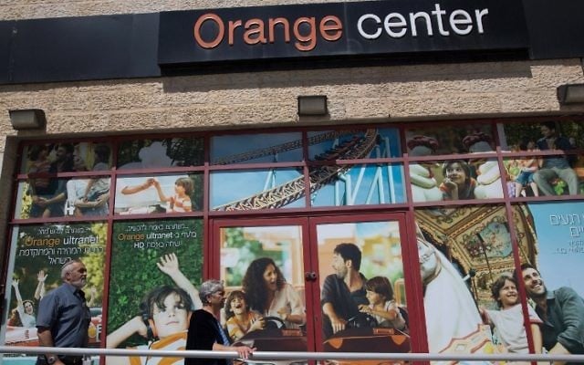 Des Israéliens passant devant un magasin de l'opérateur de télécommunications Partner, qui dispose d'une licence de la société française Orange pour utiliser sa marque, à Jérusalem le 4 juin 2015 (Crédit : AFP PHOTO / MENAHEM KAHANA)