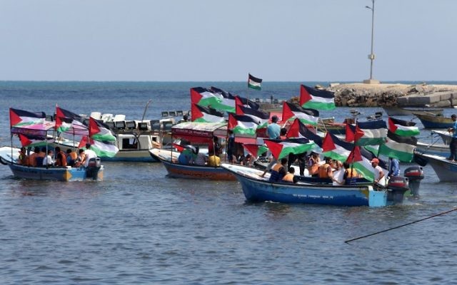 Les Palestiniens brandissent leur drapeau national lors d'un rassemblement pour montrer leur soutien aux militants à bord d'une flottille qui mettent le voile pour Gaza pour tenter de briser le blocus israélien sur Gaza, dans le port de Gaza ville, le 24 juin 2015 (Crédit : AFP / Mahmud Hams) Les Palestiniens brandissent leur drapeau national lors d'un rassemblement pour montrer leur soutien aux militants à bord d'une flottille qui mettent le voile pour Gaza pour tenter de briser le blocus israélien sur Gaza, dans le port de Gaza ville, le 24 juin 2015 (Crédit : AFP / Mahmud Hams)