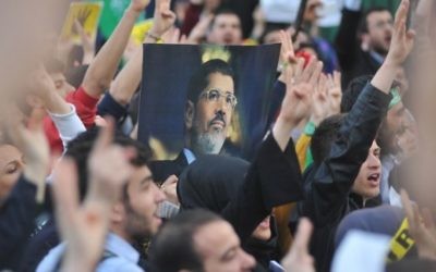 Les partisans des Frères musulmans avec un portrait du président déchu Mohammed Morsi tandis qu'ils prennent part à un rassemblement pour protester contre les peines de mort pour des membres du groupe radical en Egypte, devant l'ambassade égyptienne à Ankara le 9 avril 2014 (Crédit : AFP PHOTO / ADEM ALTAN)