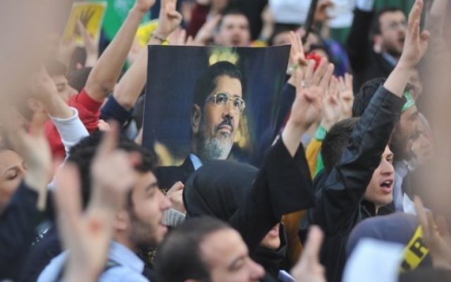 Les partisans des Frères musulmans avec un portrait du président déchu Mohammed Morsi tandis qu'ils prennent part à un rassemblement pour protester contre les peines de mort pour des membres du groupe radical en Egypte, devant l'ambassade égyptienne à Ankara le 9 avril 2014 (Crédit : AFP PHOTO / ADEM ALTAN)